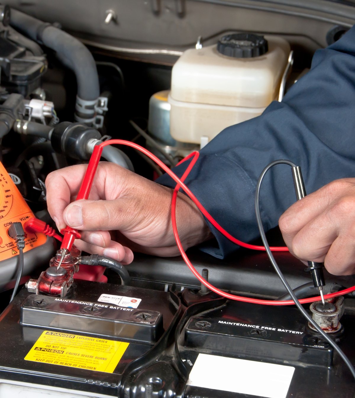 Technician testing a car battery voltage with a digital multimeter