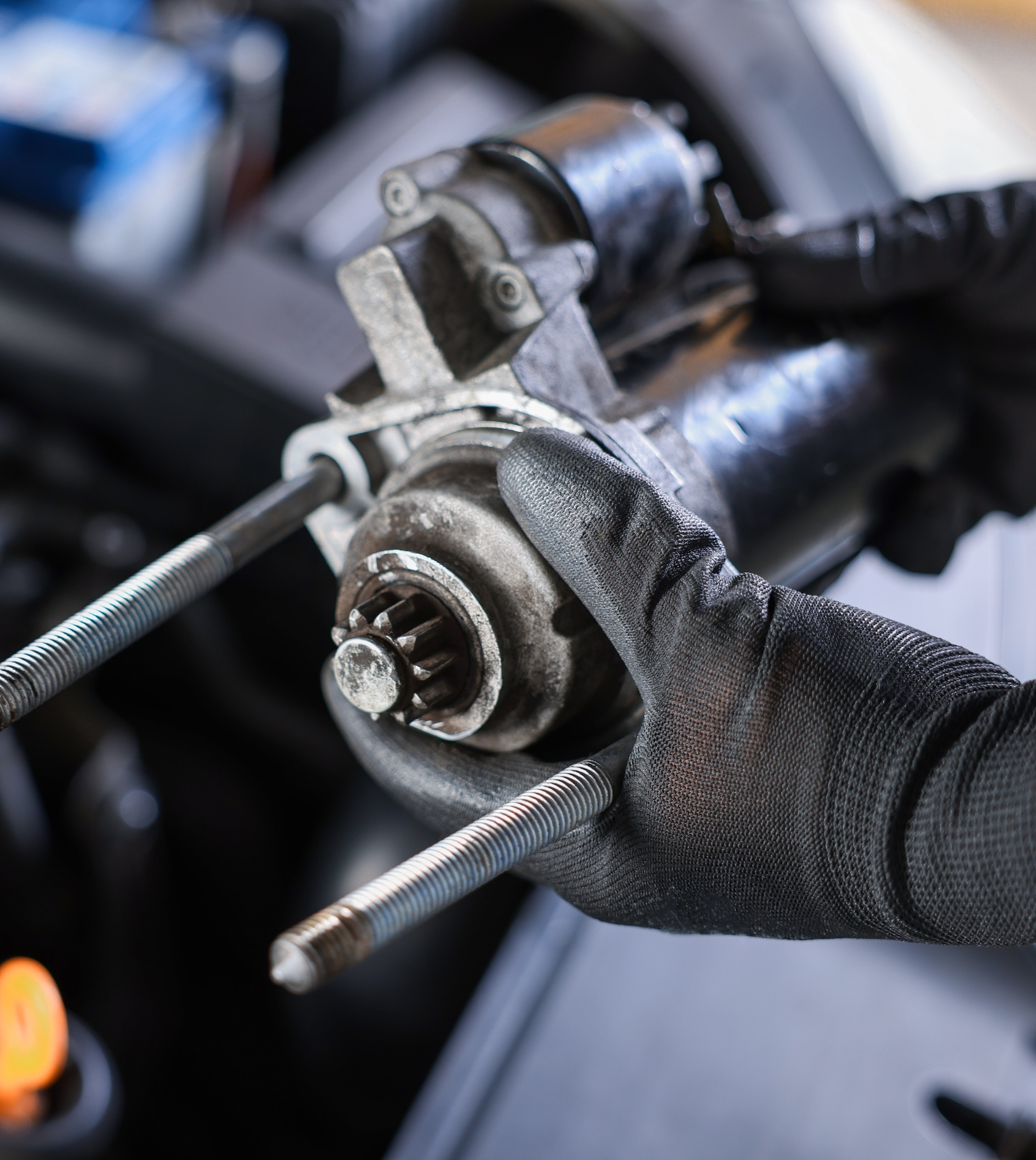 Mechanic positioning a starter motor in the engine bay