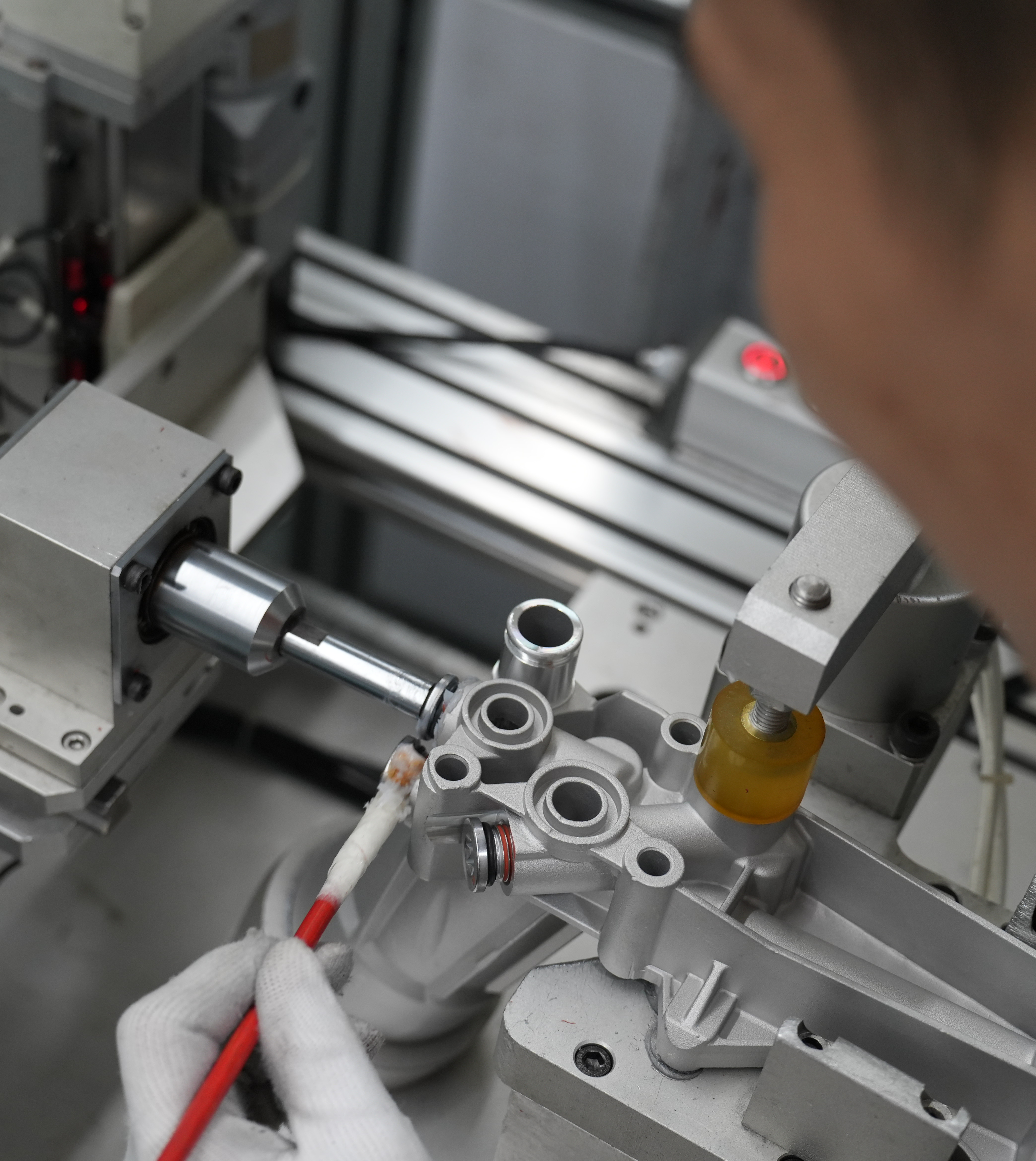 Factory worker applying lubricant during automotive oil filter housing assembly
