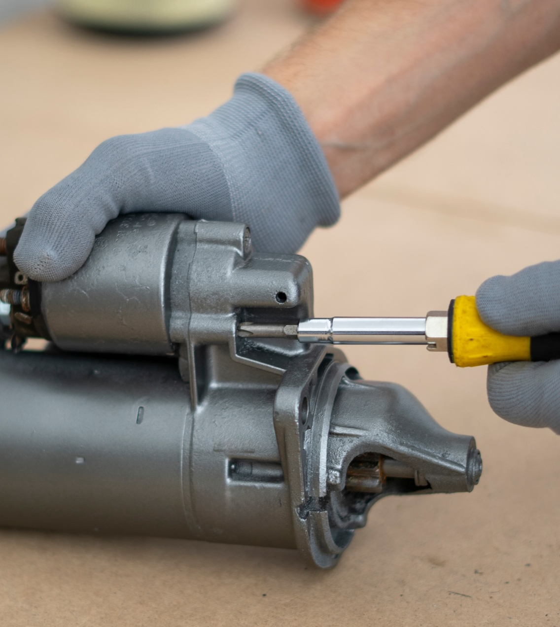 Mechanic holding a car starter motor before installation