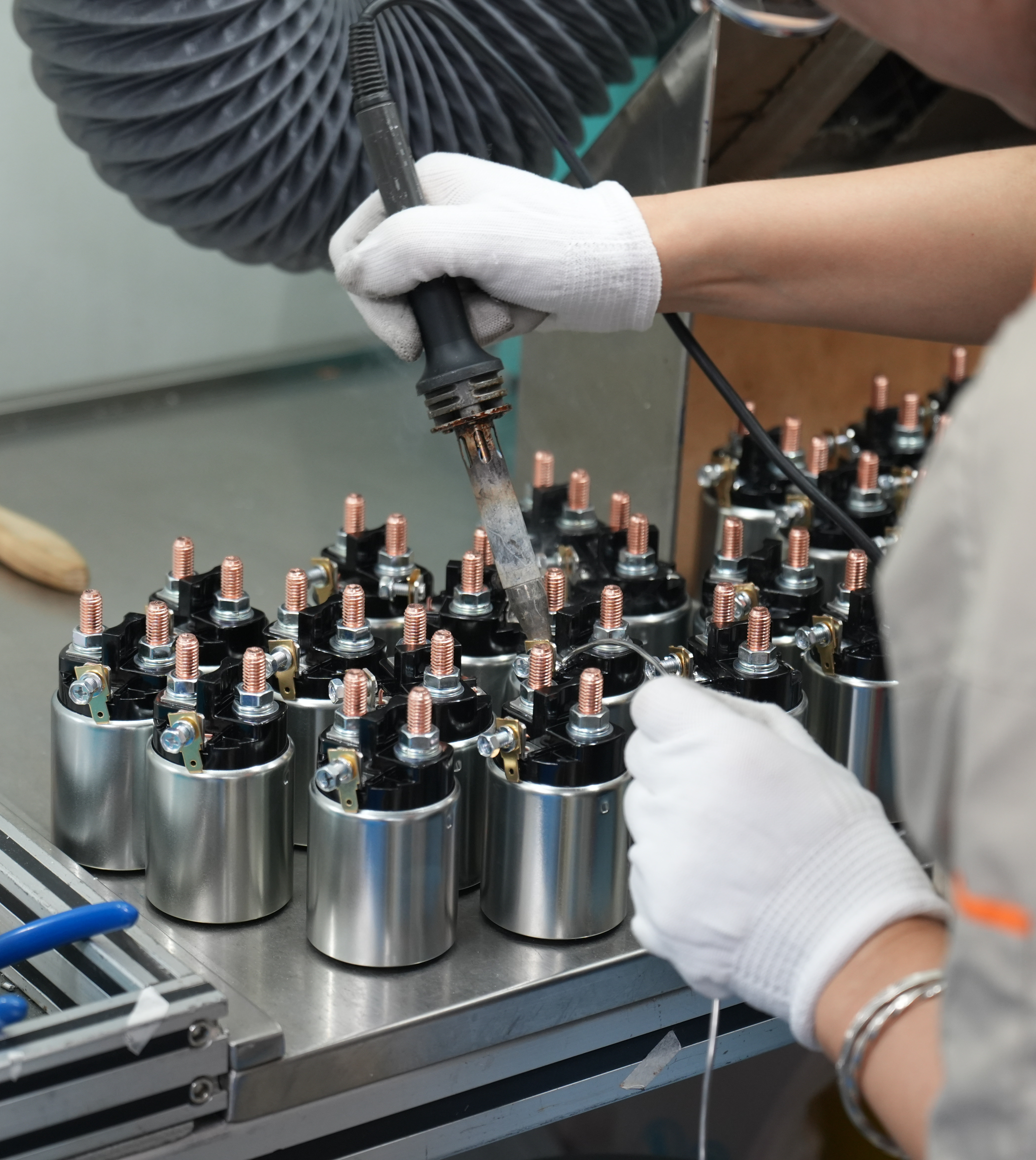 Factory worker operating a machine to assemble copper-wound automotive solenoid coils