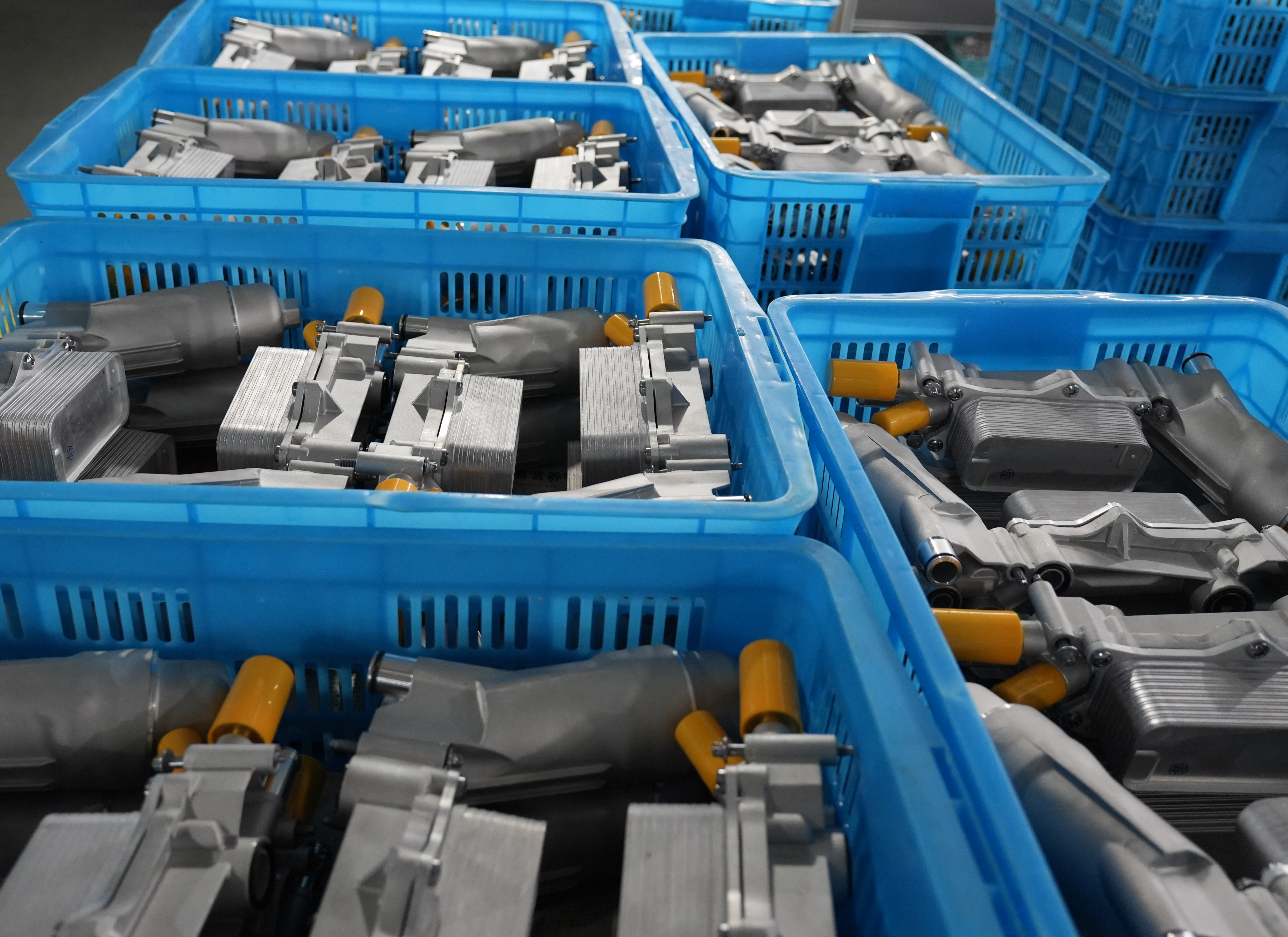 Finished aluminum automotive components stored in blue bins at a factory warehouse