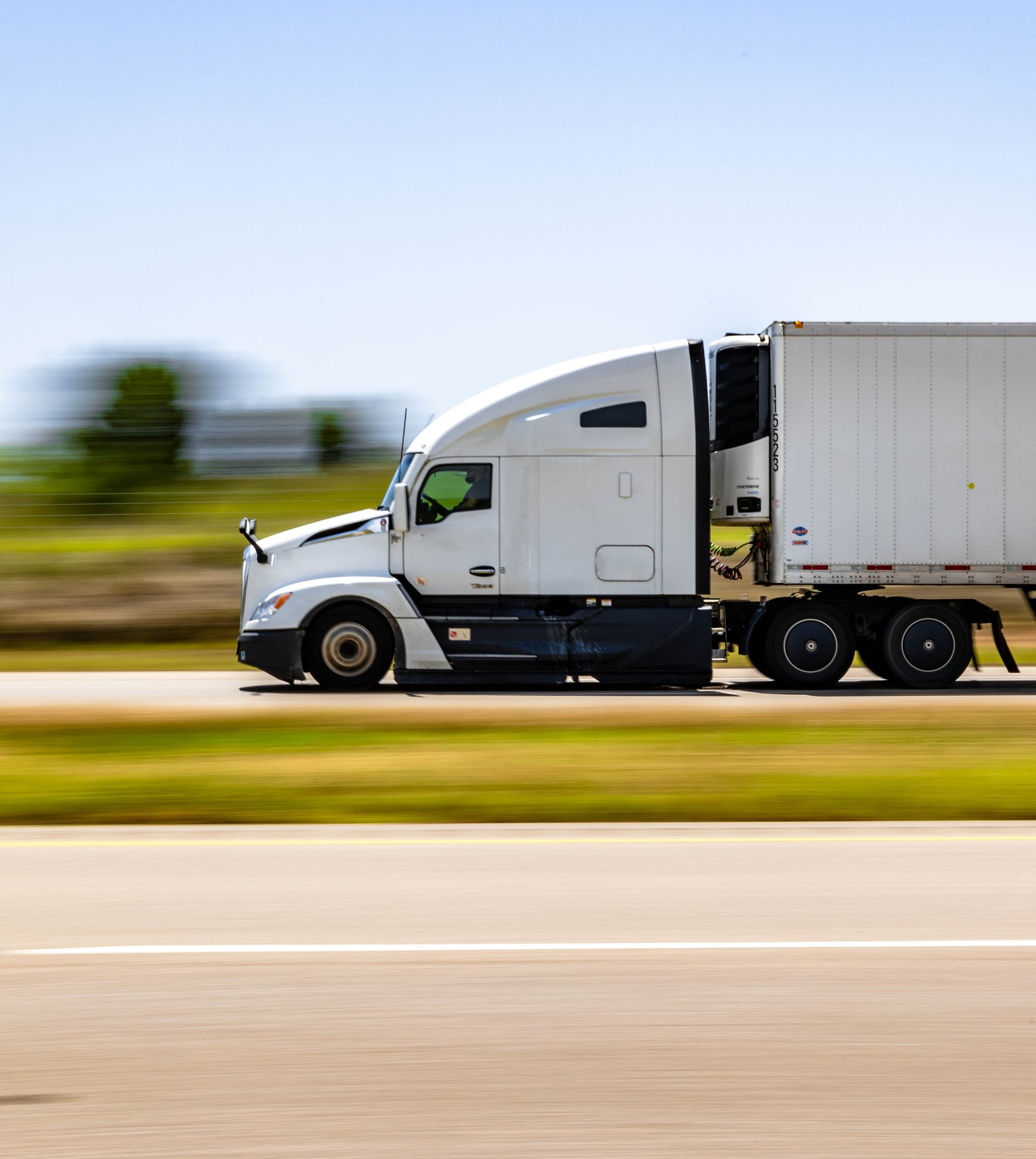 White semi-truck hauling a refrigerated trailer on a highway