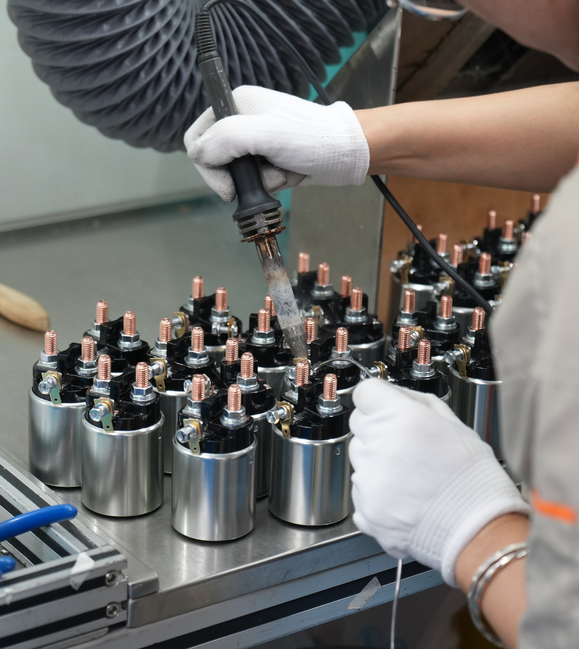 Factory worker operating a machine to assemble copper-wound automotive solenoid coils