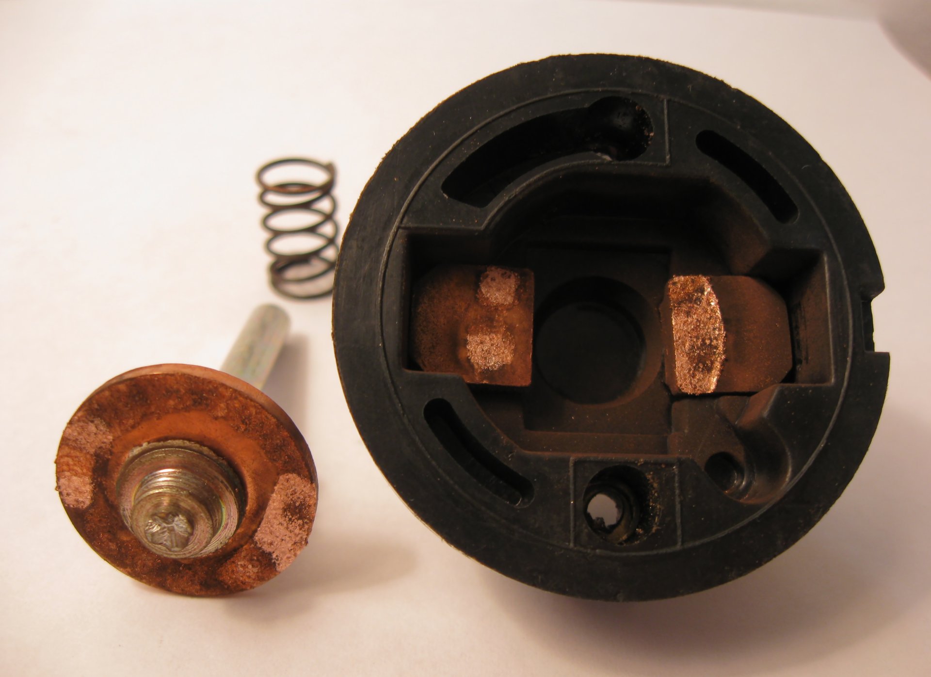 Disassembled starter solenoid showing worn copper contacts, plunger, and return spring