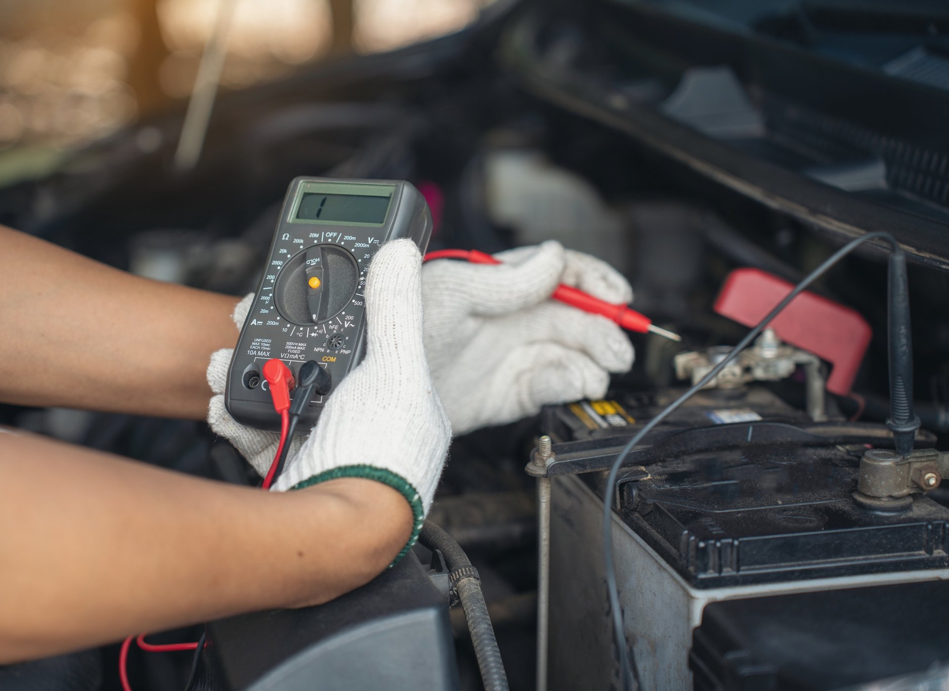 Mechanic using a digital multimeter to diagnose a car battery