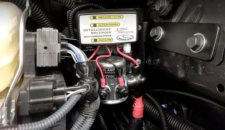Battery isolation solenoid and split charging controller installed in a vehicle engine bay